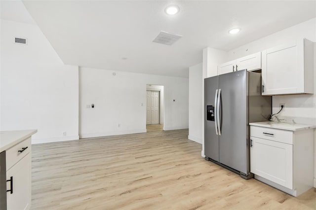 kitchen featuring light wood-style floors, white cabinetry, visible vents, and stainless steel fridge with ice dispenser
