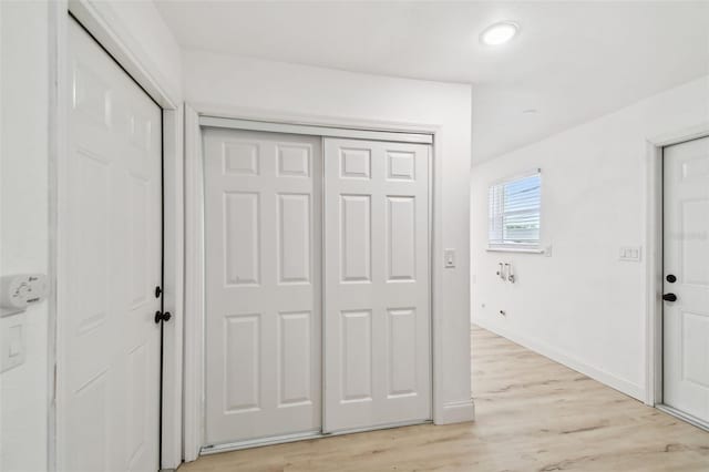 hall with light wood-style flooring and baseboards