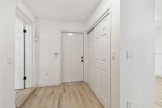 corridor with light wood-type flooring and baseboards