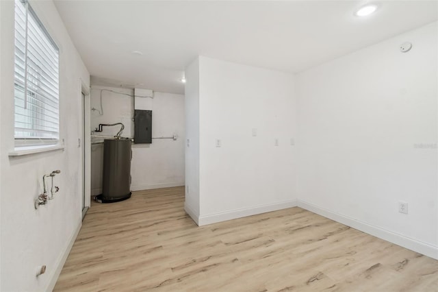 spare room featuring gas water heater, recessed lighting, baseboards, electric panel, and light wood finished floors