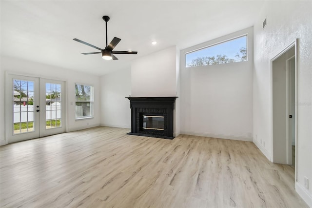 unfurnished living room featuring a brick fireplace, baseboards, wood finished floors, and french doors