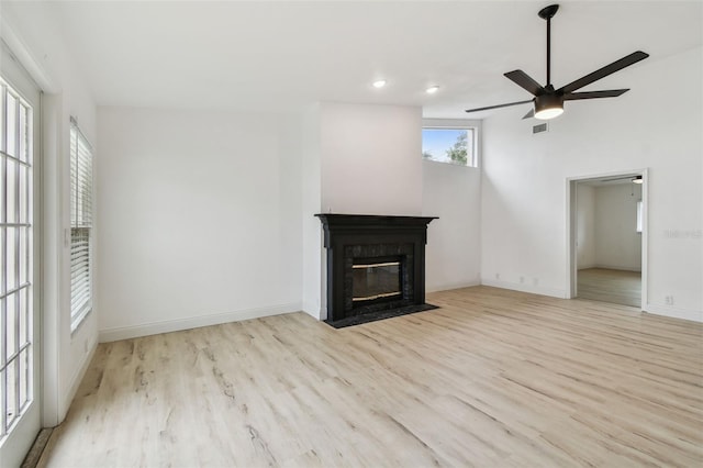 unfurnished living room with baseboards, visible vents, wood finished floors, and a high end fireplace
