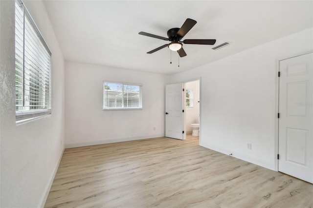 empty room with ceiling fan, wood finished floors, visible vents, and baseboards