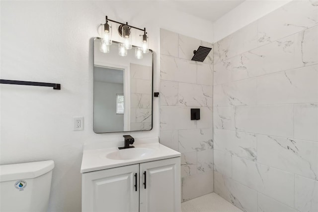 full bathroom with a tile shower, vanity, and toilet