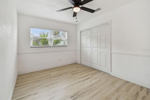 unfurnished bedroom featuring a closet, visible vents, a ceiling fan, wood finished floors, and baseboards