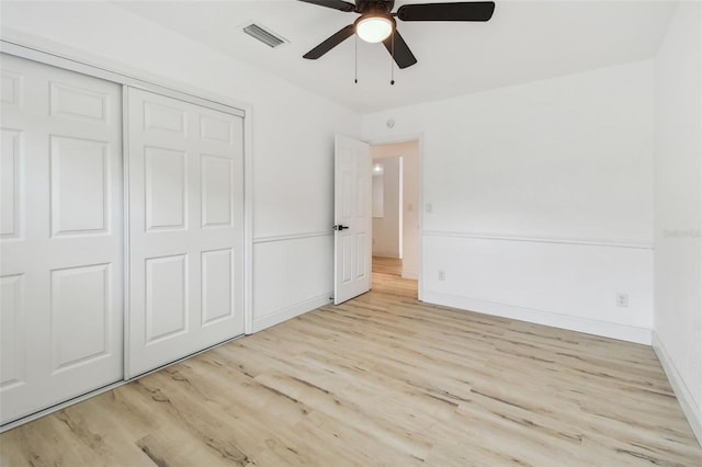 unfurnished bedroom with baseboards, visible vents, ceiling fan, wood finished floors, and a closet