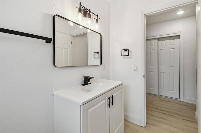 bathroom with baseboards, wood finished floors, and vanity