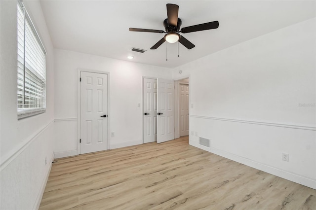 unfurnished bedroom with ceiling fan, wood finished floors, visible vents, and baseboards
