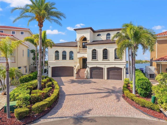 mediterranean / spanish-style home with decorative driveway, a balcony, an attached garage, and stucco siding