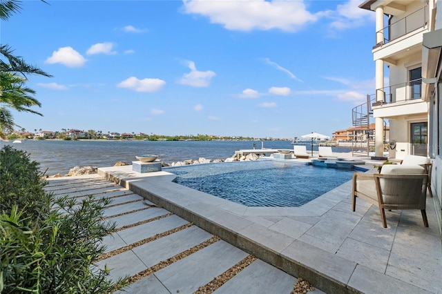 view of swimming pool featuring an in ground hot tub, an infinity pool, a patio, and a water view