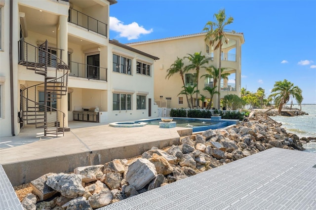 exterior space featuring stairs, a patio area, a water view, and stucco siding