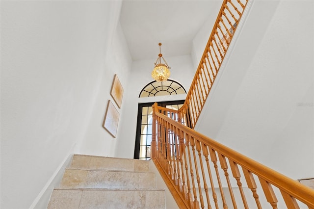 stairway with a high ceiling and an inviting chandelier