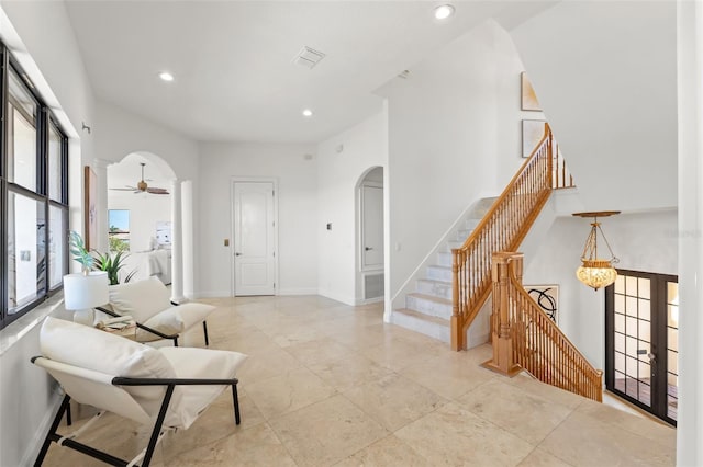 entrance foyer featuring visible vents, baseboards, recessed lighting, a towering ceiling, and arched walkways