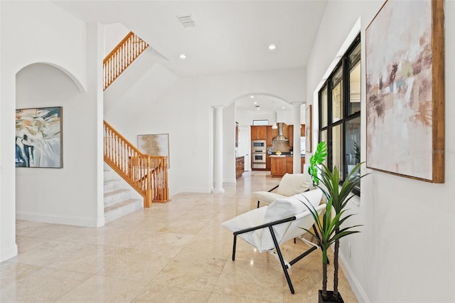 interior space with stairway, baseboards, visible vents, and ornate columns