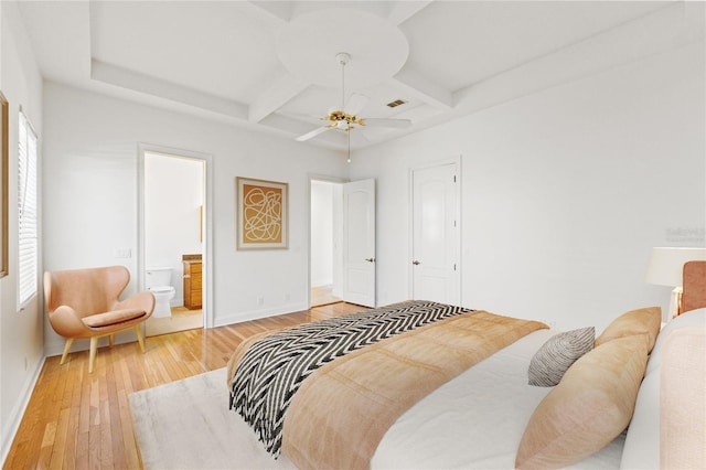 bedroom with light wood finished floors, visible vents, baseboards, ensuite bathroom, and coffered ceiling