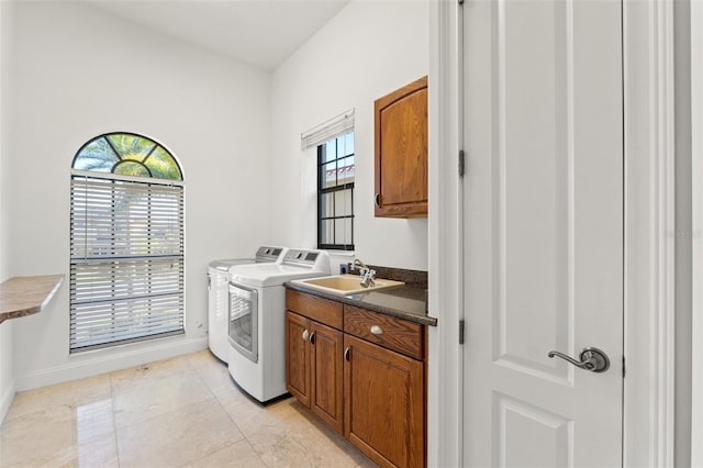 clothes washing area with baseboards, washer and clothes dryer, light tile patterned floors, cabinet space, and a sink