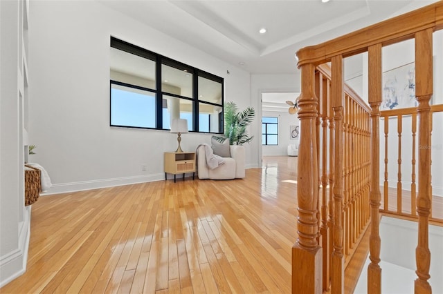 unfurnished room with recessed lighting, baseboards, light wood-type flooring, and a tray ceiling