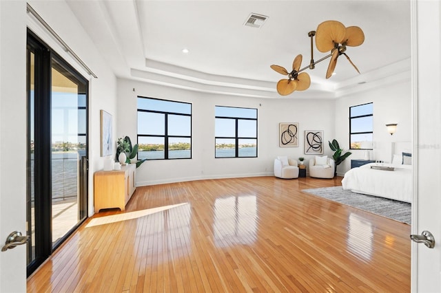 unfurnished bedroom with a raised ceiling, baseboards, visible vents, and light wood finished floors