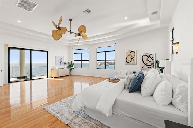 bedroom featuring recessed lighting, visible vents, light wood-style flooring, and a tray ceiling