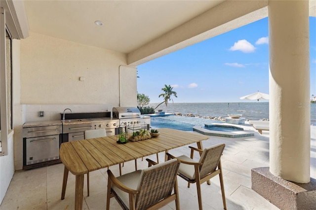 view of patio / terrace with grilling area, a pool with connected hot tub, a water view, exterior kitchen, and a sink