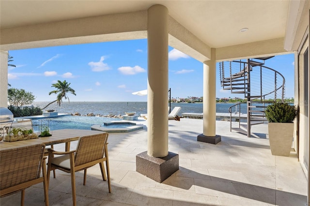 view of patio featuring outdoor dining space, a pool with connected hot tub, and a water view