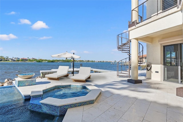 view of patio / terrace featuring stairway, a water view, and an in ground hot tub