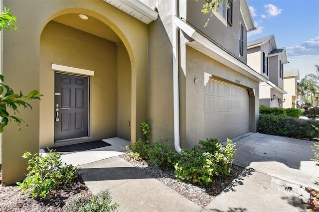 doorway to property featuring a garage and stucco siding