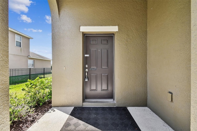 property entrance featuring fence and stucco siding