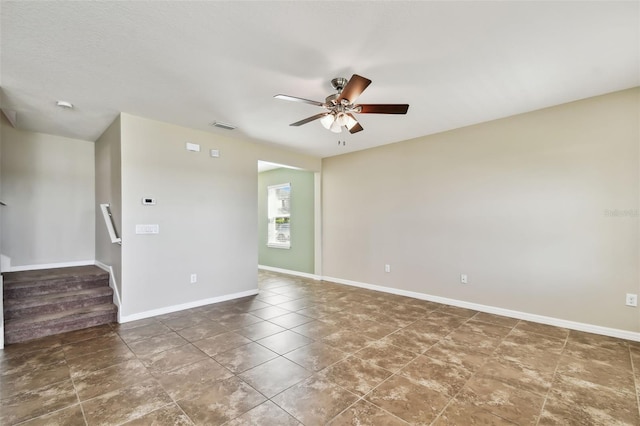 spare room featuring a ceiling fan, visible vents, stairway, and baseboards