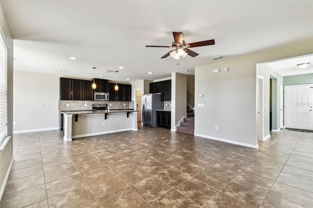 kitchen with a breakfast bar area, stainless steel appliances, tasteful backsplash, visible vents, and open floor plan