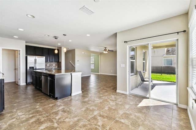 kitchen with stainless steel appliances, dark cabinetry, a center island with sink, and visible vents