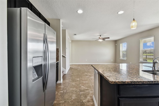 kitchen featuring dark cabinets, a sink, a textured ceiling, and stainless steel fridge with ice dispenser