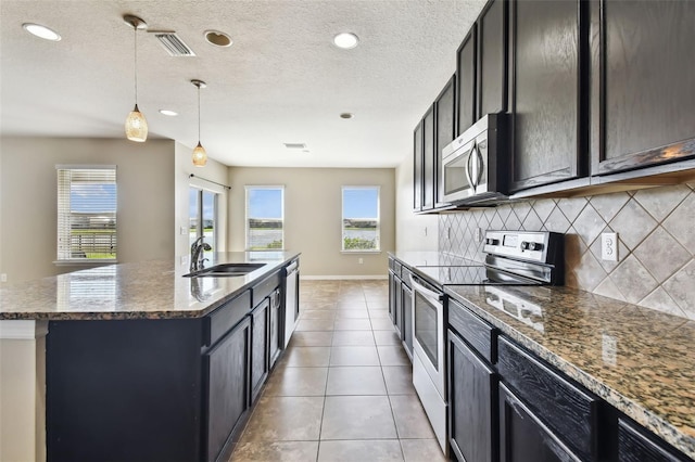 kitchen featuring visible vents, decorative backsplash, appliances with stainless steel finishes, light tile patterned flooring, and a sink