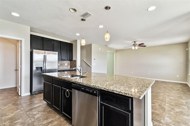 kitchen with a kitchen island with sink, dark cabinets, stainless steel appliances, a sink, and visible vents