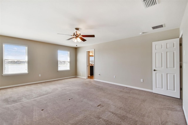 spare room featuring carpet, visible vents, ceiling fan, and baseboards