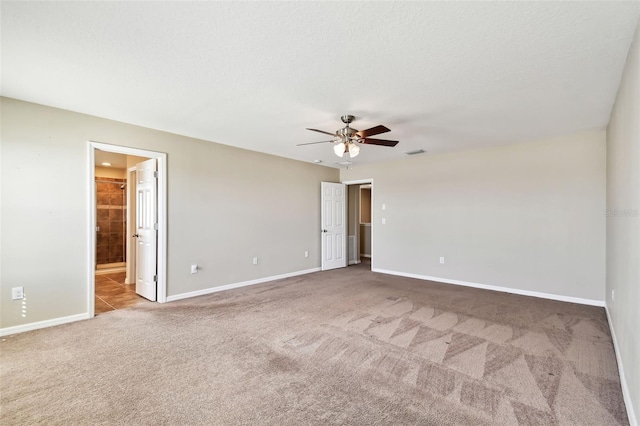 carpeted spare room with a ceiling fan, visible vents, and baseboards