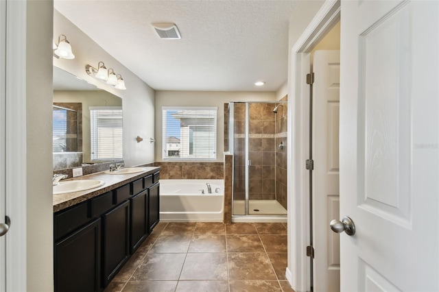 full bathroom featuring a textured ceiling, a sink, a bath, and a shower stall