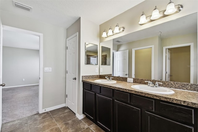 bathroom with double vanity, baseboards, visible vents, and a sink