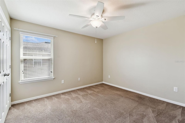 empty room featuring baseboards, a ceiling fan, and carpet flooring