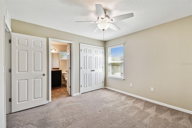 unfurnished bedroom featuring baseboards, ensuite bathroom, a textured ceiling, carpet floors, and a closet