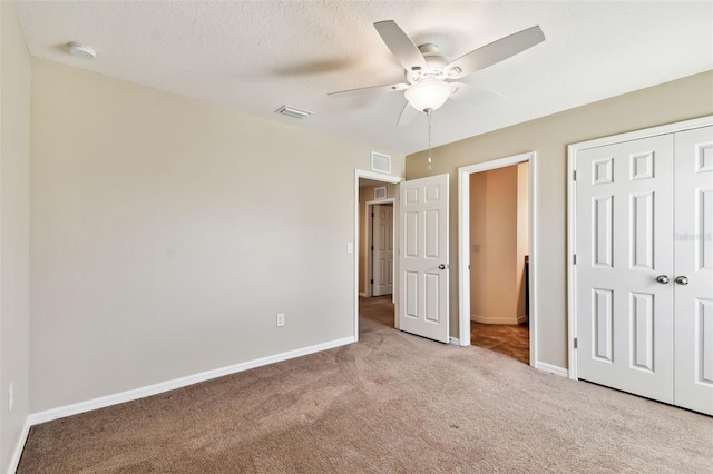 unfurnished bedroom with a textured ceiling, visible vents, baseboards, a closet, and carpet