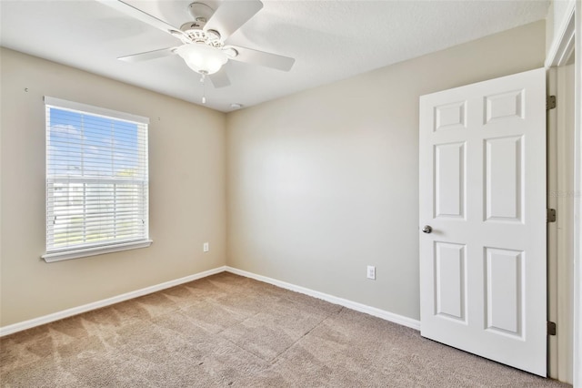 spare room with carpet, ceiling fan, and baseboards