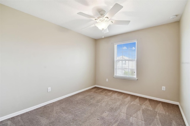 carpeted spare room featuring ceiling fan and baseboards