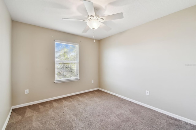 carpeted empty room with ceiling fan and baseboards