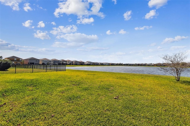 view of yard featuring a water view, a residential view, and fence