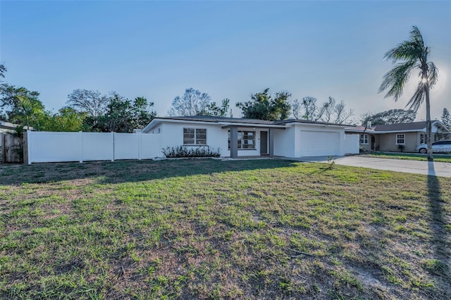 ranch-style home with a garage, fence, driveway, stucco siding, and a front yard