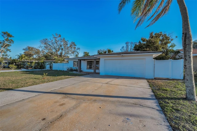 view of front of home featuring stucco siding, concrete driveway, an attached garage, fence, and a front lawn