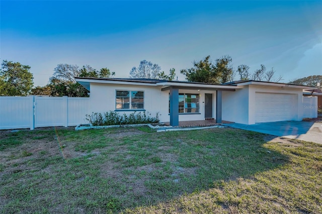 view of front of house with driveway, stucco siding, an attached garage, fence, and a front yard