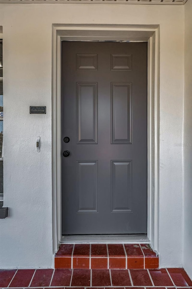 doorway to property featuring stucco siding