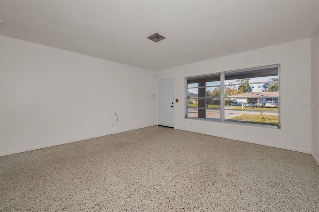 empty room featuring visible vents, baseboards, and speckled floor